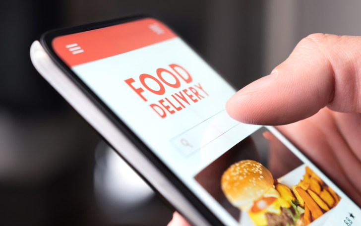 Restaurant food delivery service in phone. Take away menu in digital mobile app. Man ordering takeout pizza or burger online. Fast lunch delivered home. Person using smartphone and mockup application.