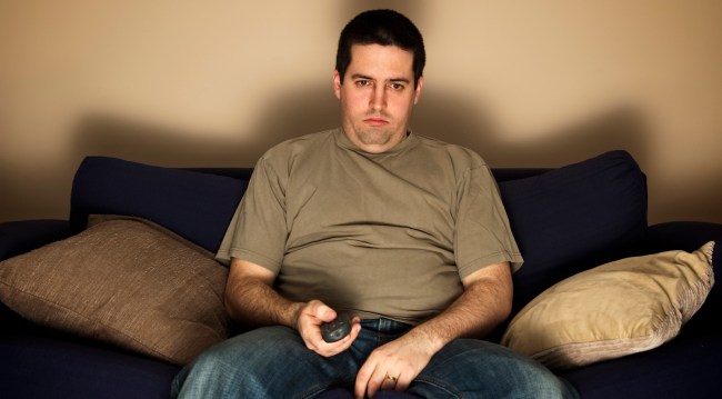 Bored, lazy, overweight man sits on the sofa