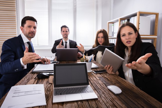 Portrait Of Shocked Young Businesspeople Sitting In Office