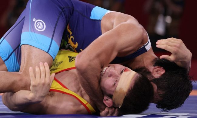 TOPSHOT - Kazakhstan's Nurislam Sanayev (red) bites India's Kumar Ravi as he wrestles him in their men's freestyle 57kg wrestling semi-final match during the Tokyo 2020 Olympic Games at the Makuhari Messe in Tokyo on August 4, 2021.