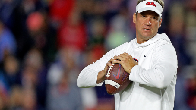 Lane Kiffin holds a football.