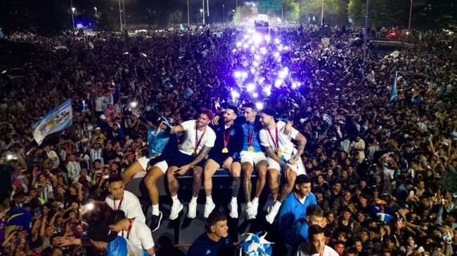 Argentina's captain and forward Lionel Messi (C) holds the FIFA World Cup Trophy on board a bus as he celebrates alongside teammates and supporters after winning the Qatar 2022 World Cup tournament in Ezeiza, Buenos Aires province, Argentina on December 20, 2022
