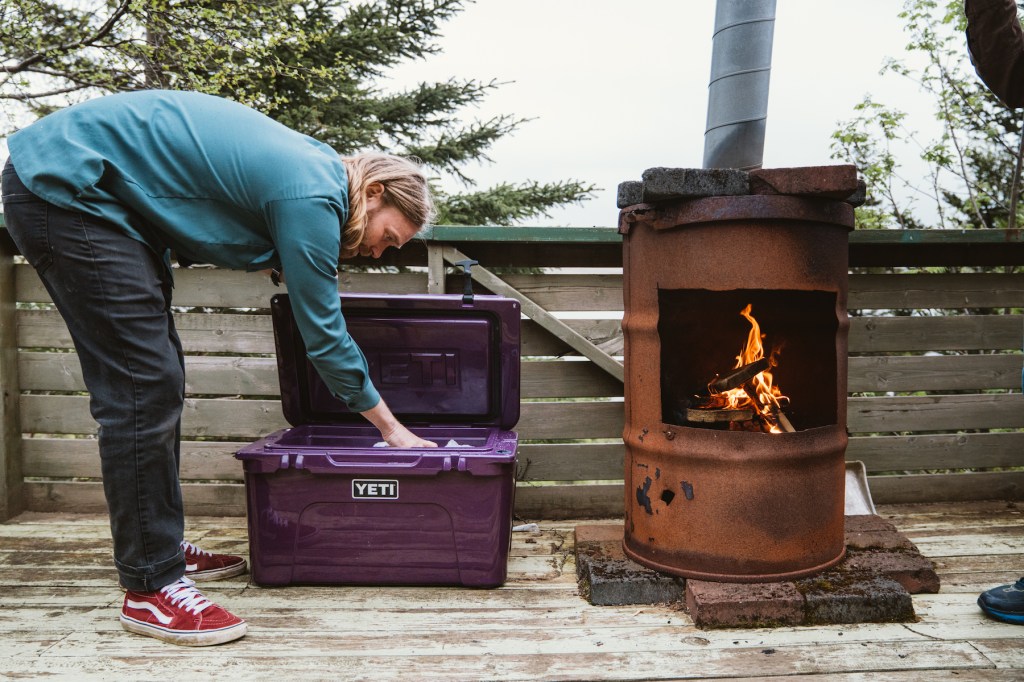 Man pulling out a beverage from a Yeti Nordic Purple Cooler