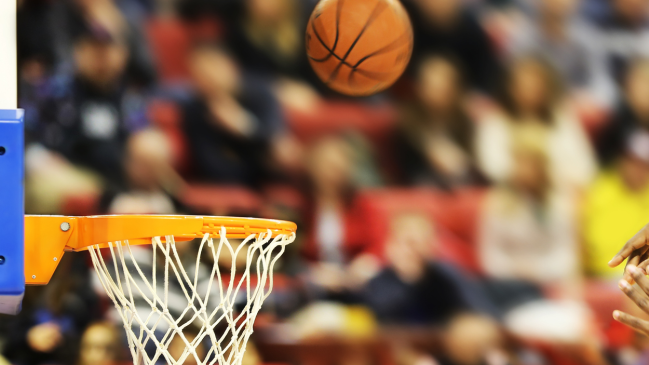 A player shoots a basketball towards a hoop.