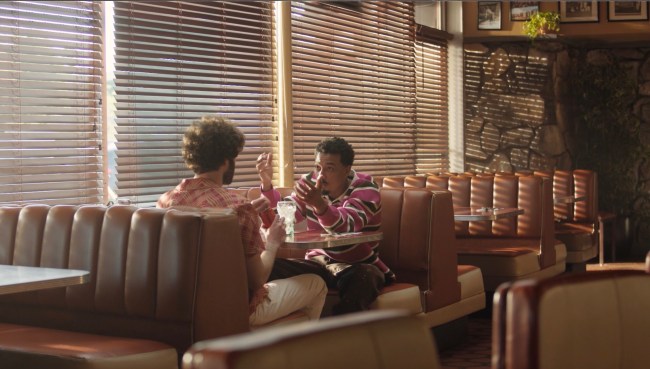 Lil Dicky and Travis Bennett sitting in a diner booth in the new Coke Zero Sugar commercial 