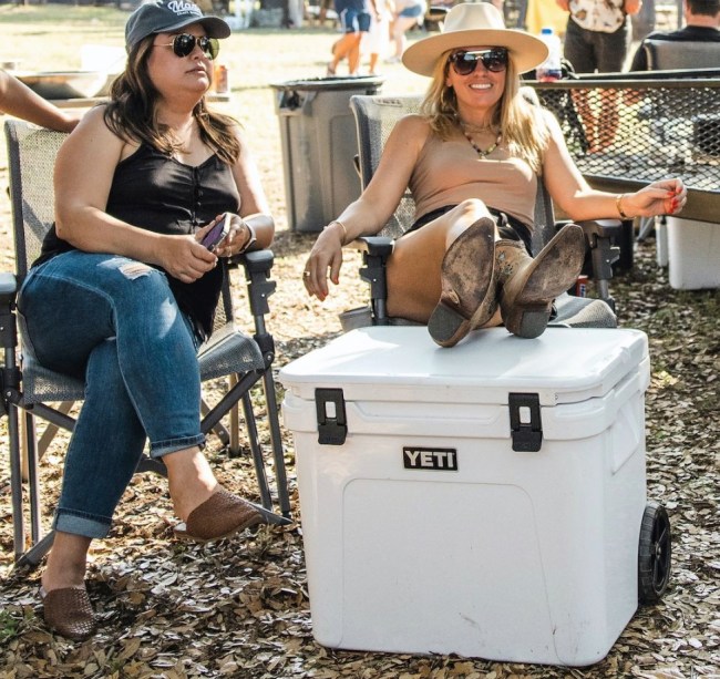 Picture of a woman resting her legs on a YETI cooler at a outdoor picnic
