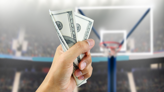 A fan holds up money for a basketball bet.