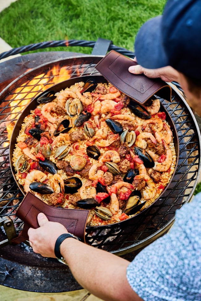 Smithey Ironworks cooking seafood paella on a fire