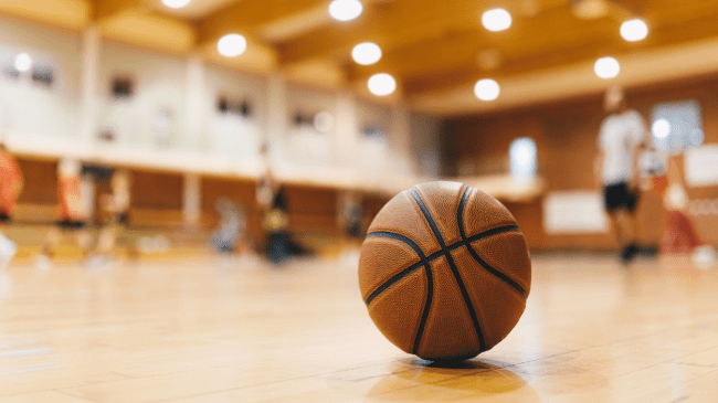 A basketball rests on a gym floor.