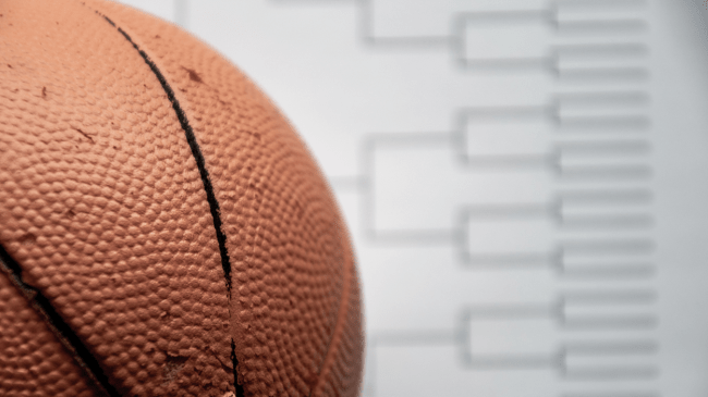 An image of a basketball in front of a March Madness bracket.