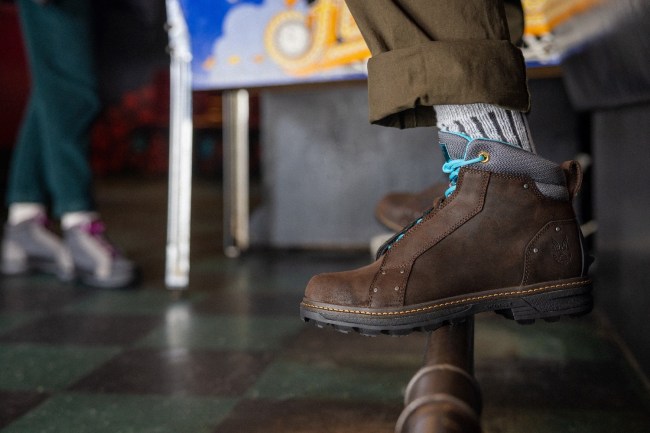 The Wolverine x Halo brown leather boot collab with sky blue laces, worn by a man in a casual bar setting