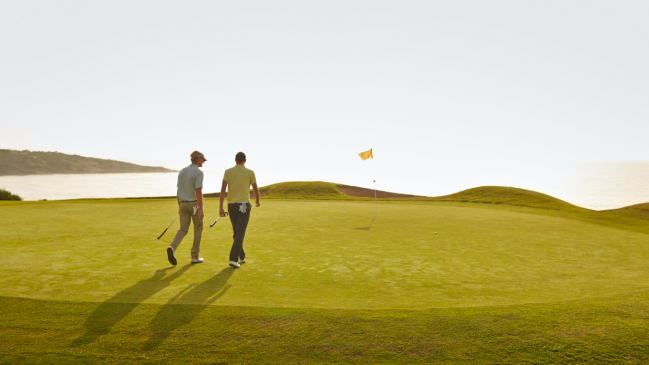Two golfers walk the green.