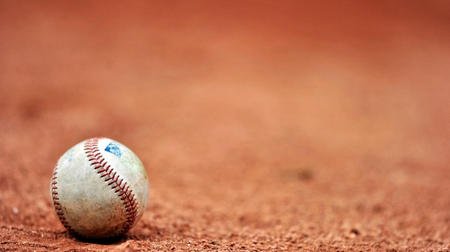 A baseball rests on the infield clay.