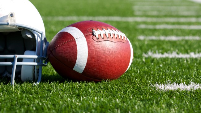 A football rests next to a helmet on the field.