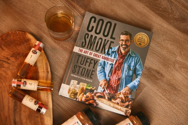 Pitmaster Tuffy Stone's book Cool Smoke on a wooden table with whiskey