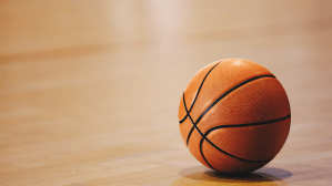 A basketball rests on a gym floor.