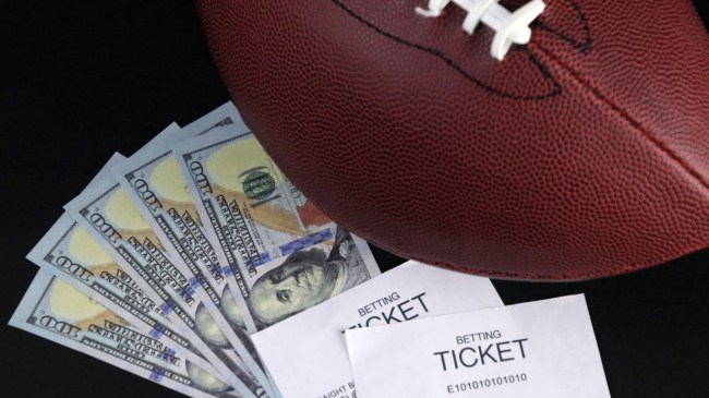 A football sits beside money and sports betting tickets.