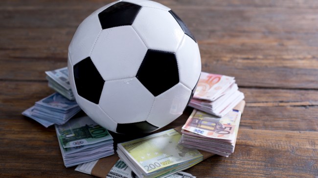 A soccer ball sits on top of a pile of money.