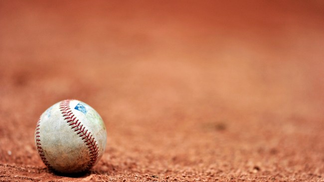 A baseball sits on the infield clay.