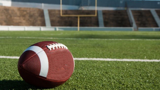 A football sits on the field with uprights in the background.