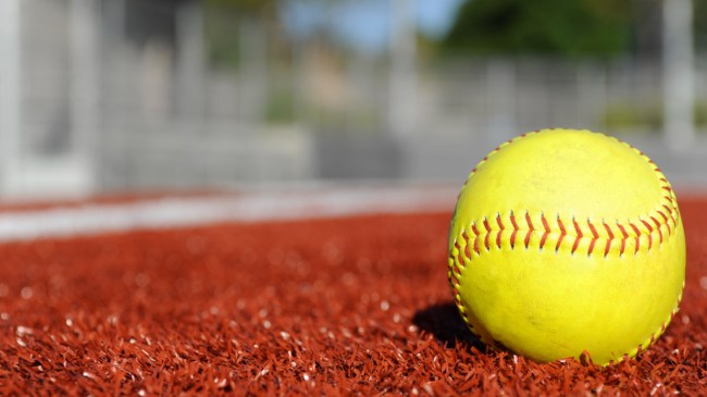 A softball sits on the infield clay.