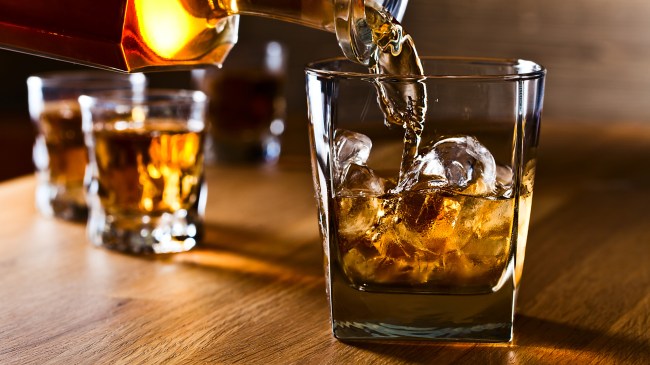 Whiskey being poured into a glass over ice