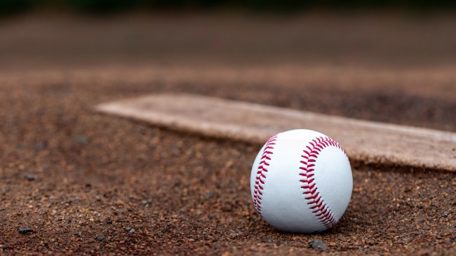 A baseball rests beside a pitching rubber on the mound.