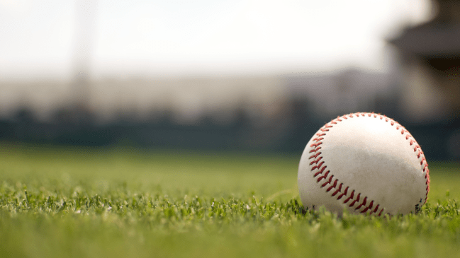 A ball lays in the outfield grass of a baseball field.