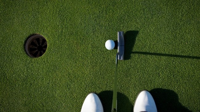 A golfer lines up a putt on the green.