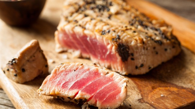 A piece of grilled tuna on a cutting board.