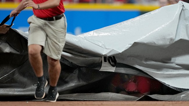 A grounds crew member gets trapped under the tarp.