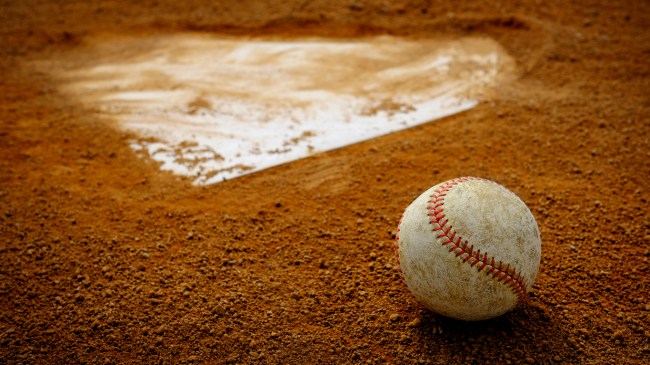 A baseball rests in the clay behind home plate.