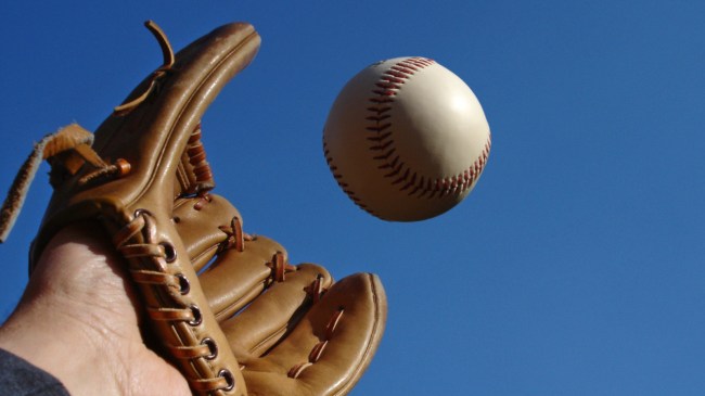A glove reaches up to catch a baseball.