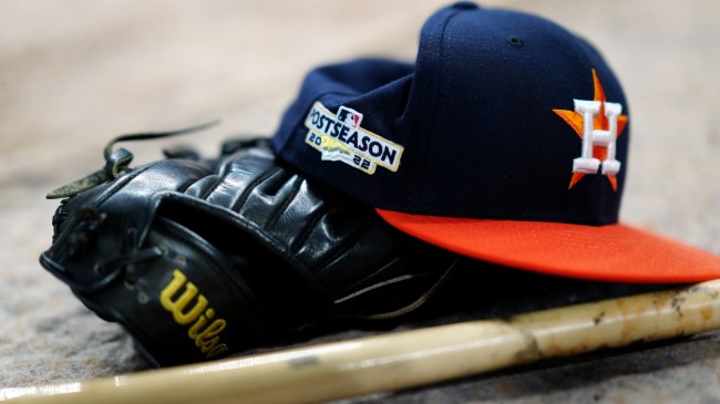 A Houston Astros hat beside a glove and baseball bat.