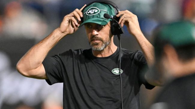 aaron rodgers wearing a headset on the sidelines of a jets game
