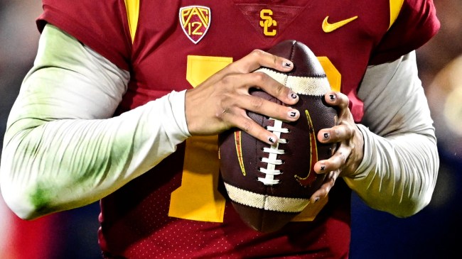 Caleb Williams holds a football with a message written along his fingernails.