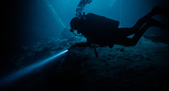 scuba diver with flashlight under water