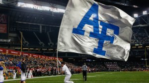 An Air Force cheerleader runs with a flag through the endzone during a football game.