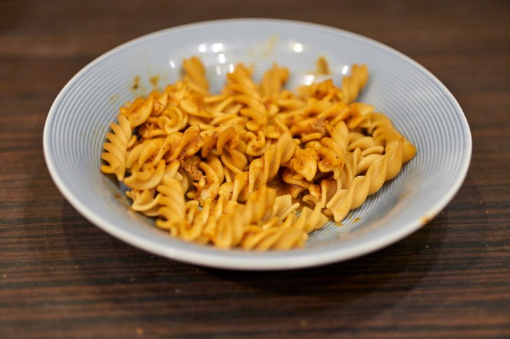 A closeup shot of a plate with fusilli pasta on a wooden table