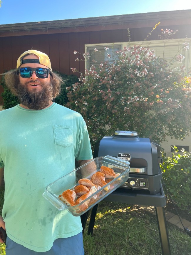 Bearded man holding chicken before using Ninja Woodfire™ Pro Connect XL Outdoor Grill & Smoker