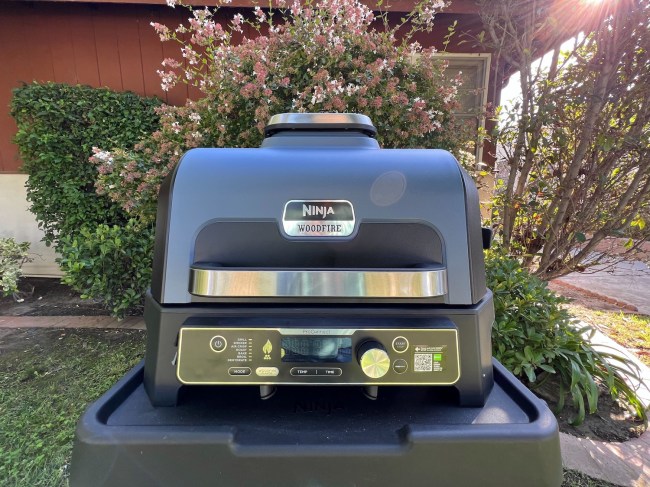 The Ninja Woodfire™ Pro Connect XL Outdoor Grill & Smoker outside a home 