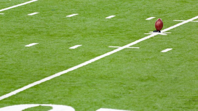 A football sits on a tee at midfield.