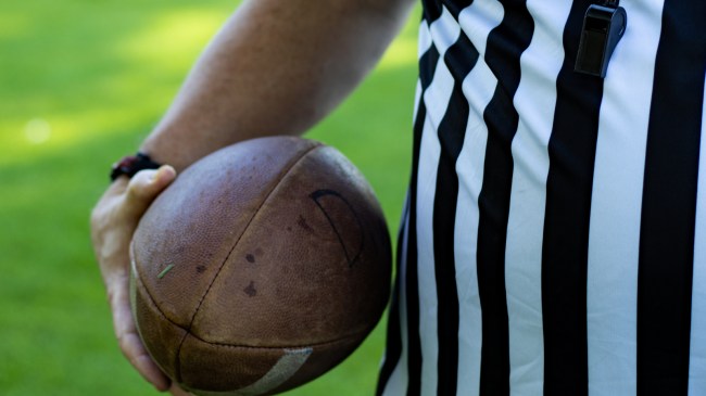 A referee holds a football before spotting it on the field.