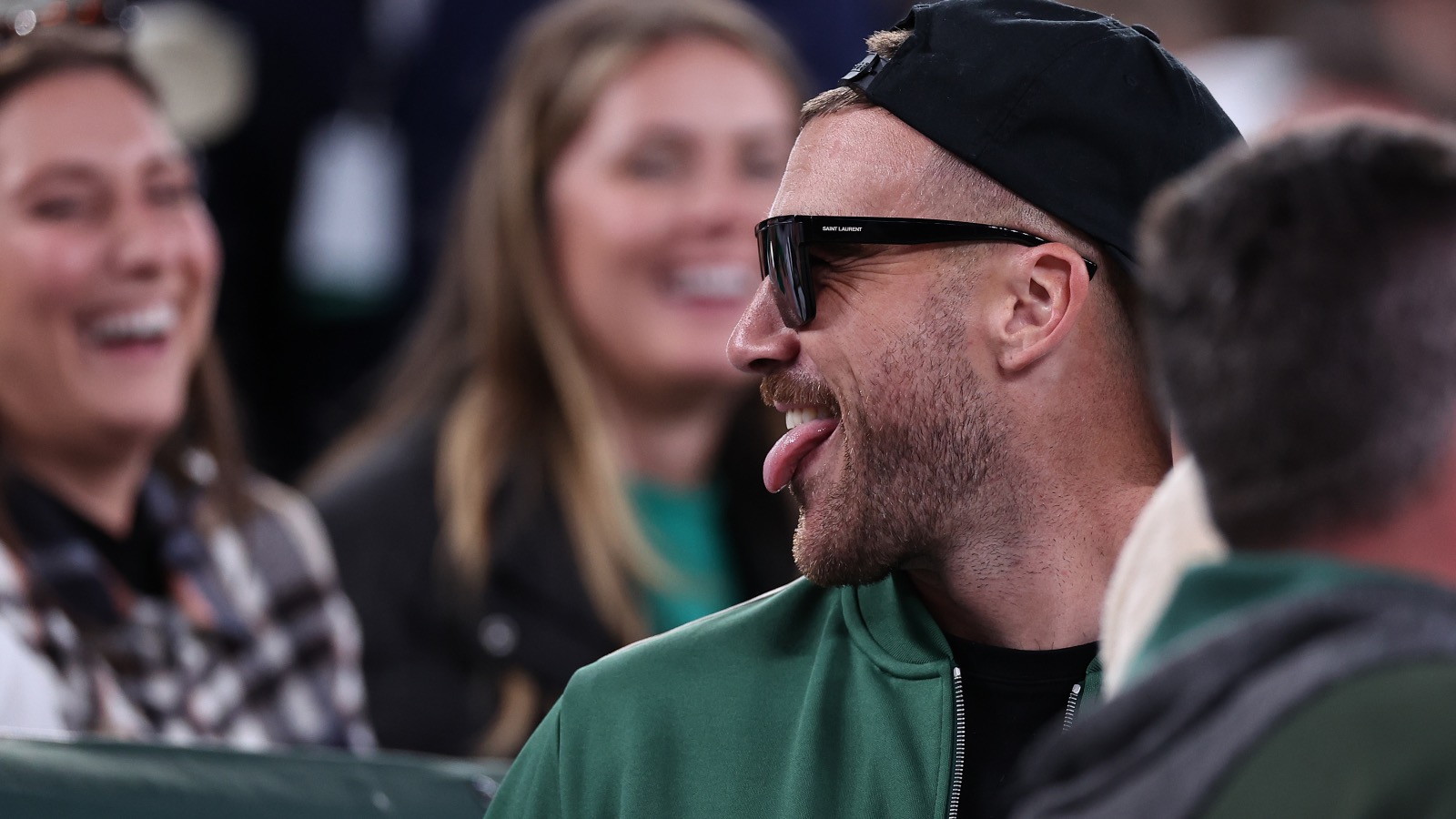 Travis Kelce smiling on the sidelines at the Jets game