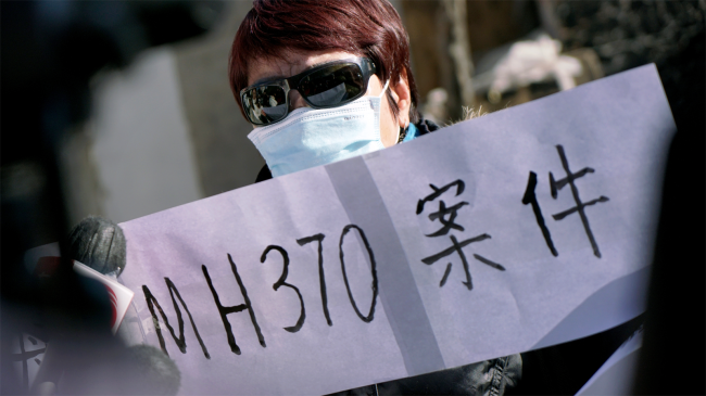 relative of passenger of missing Malaysia Airlines flight MH370 holds sign