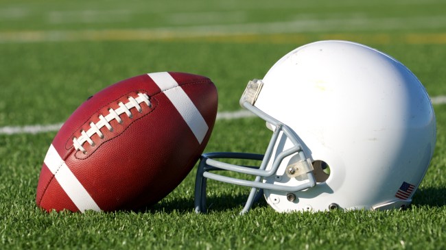 A football rests beside a helmet on the playing field.
