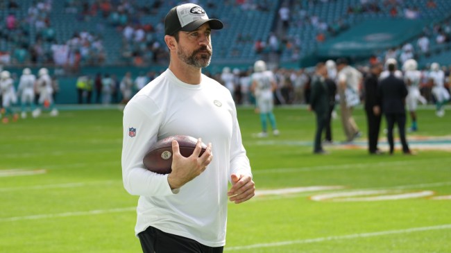 Aaron Rodgers holds a football on the sidelines before a New York Jets game.