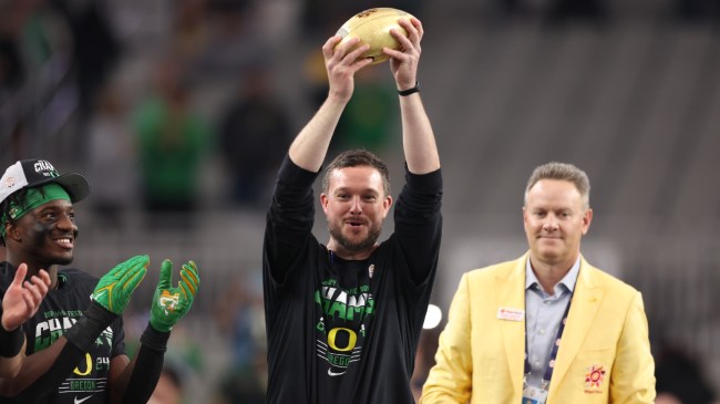 Dan Lanning holds a trophy after a bowl game win.