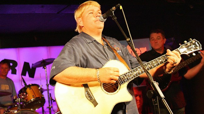 John Daly plays guitar on stage.