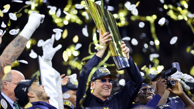 Jim Harbaugh holds the national championship trophy after Michigan beats Washington.